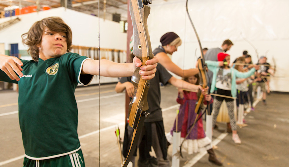 Kid drawing a bow at the Trackers SE indoor archery range