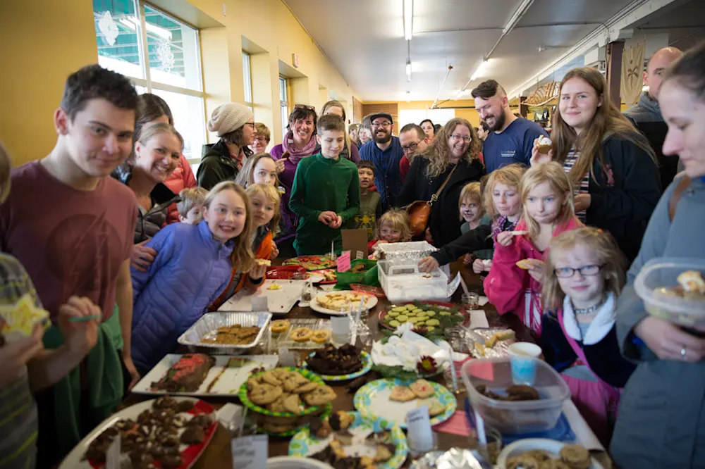 A crowd of kids and grown-ups gathered around the holiday cookie table
