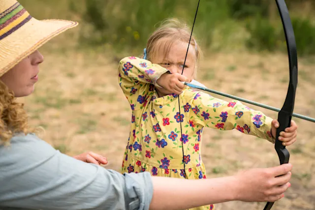 Young camper drawing a bow