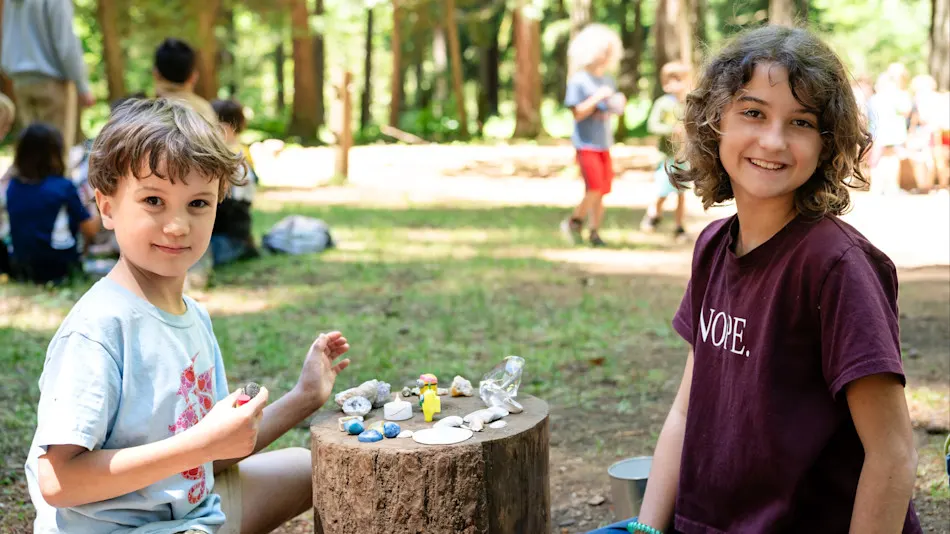 Two kids at a stump table covered in trinkets at the Goblin Market