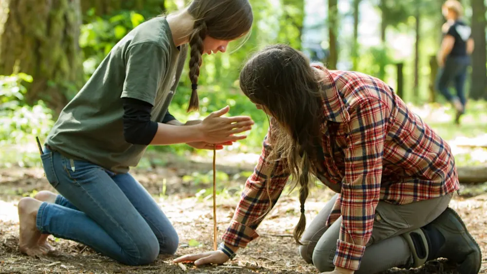 Teens making fire by friction in the forest
